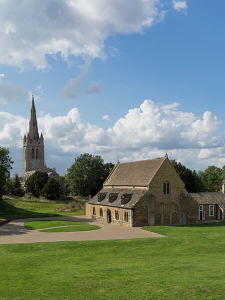 Oakham Castle on a beautiful day with the All Saints Church in the background in Oakham, Rutland, England, UK.