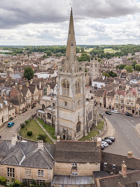 Aerial photography of the town centre of Stamford, Lincolnshire, UK. Showing a blue sky with clouds, pretty rooftops and many church spires.